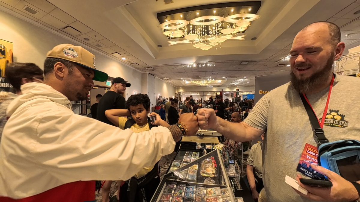 A Triple Threat Games & Hobbies team member fist-bumping a customer at the Maximum Card Show booth.